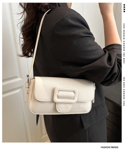 Detail of minimalist white flap shoulder bag with large square buckle on a black blazer