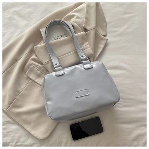 Detail of light blue oil wax leather handbag with metallic logo on white fabric