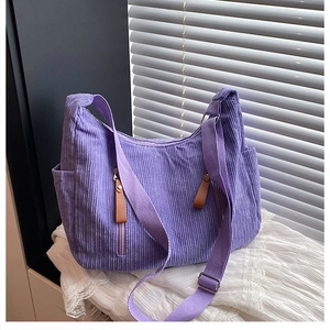 Detail of purple corduroy dumpling bag featuring side pockets and metal strap buckle