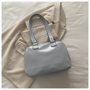 Detailed top view of light blue oil wax leather tote bag on beige blazer background