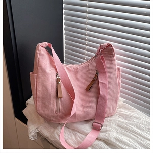 Close-up of pink corduroy dumpling bag featuring two vertical zipper pockets and strap