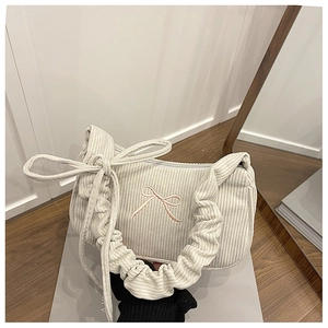 Close-up of off-white corduroy shoulder bag featuring pink bow embroidery and pleated handle