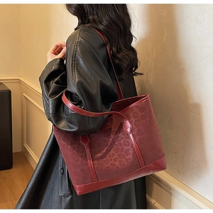 Détail du sac à bandoulière léopard bordeaux avec bordures et anses en cuir verni