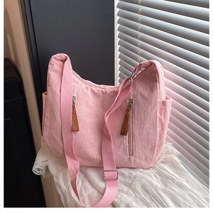 Detailed texture of pink corduroy shoulder bag with metal buckle and leather zipper pulls