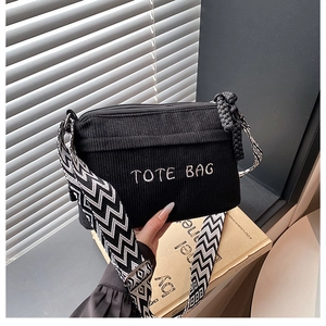 Detalle del bolso tote de pana negra con bordado blanco y correa con patrón geométrico