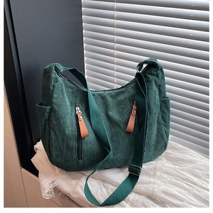 Detail view of forest green corduroy shoulder bag showing dual front zipper pockets