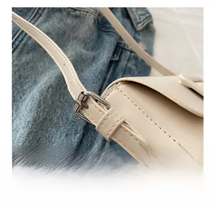 Detail of adjustable silver buckle and stitched PU leather strap on beige shoulder bag