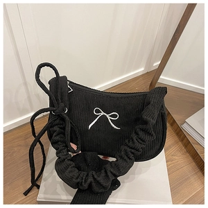 Detail of black corduroy shoulder bag with white bow embroidery and ruffled strap design