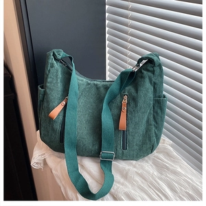Detailed close-up of dark green corduroy sling bag with dual vertical zipper pockets