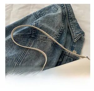 Detail of white textured leather shoulder bag with a square buckle on denim background