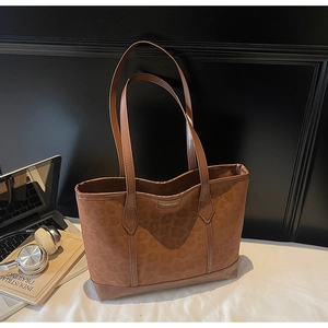 Sac fourre-tout à imprimé léopard marron avec garniture en cuir sur un lit blanc moderne