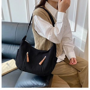 Detailed texture of black corduroy dumpling bag with decorative zipper and leather pullers