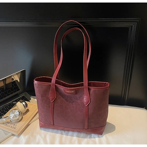 Détail d'un sac cabas bordeaux avec texture léopard sur un bureau de travail chic