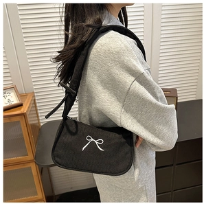Detail of black corduroy shoulder bag with white bow embroidery and adjustable strap