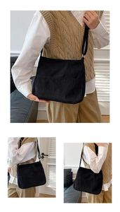 Detail view of black corduroy crossbody bag with front pocket and slim strap