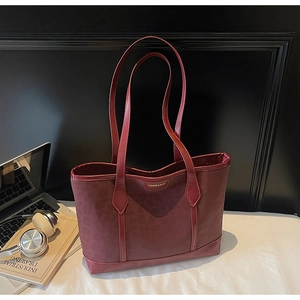 Détail d'un grand sac cabas bordeaux en cuir avec motif léopard et lettrage doré de mode