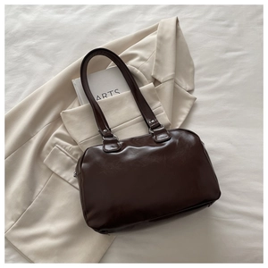Detail of dark brown oil wax leather shoulder bag on a beige blazer with silver ring buckle