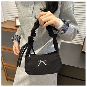 Detailed view of black corduroy shoulder bag with white bow embroidery and pleated handle