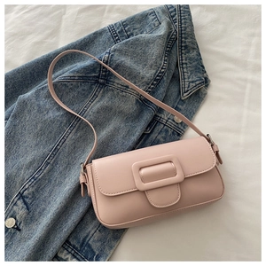Detail shot of pale pink flap shoulder bag with a stylish square buckle on a denim jacket