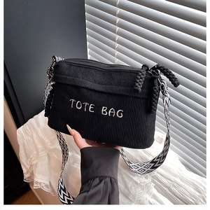 Close-up of black corduroy tote bag with TOTE BAG embroidery and geometric strap