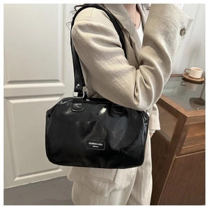 Close-up of black oil-wax leather handbag with silver rings and brand label