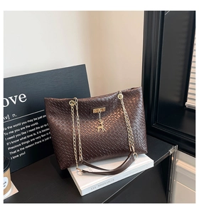 Detailed view of dark brown woven bucket bag with gold deer pendant and chain strap