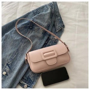 Pink faux leather baguette bag with decorative square buckle next to a smartphone