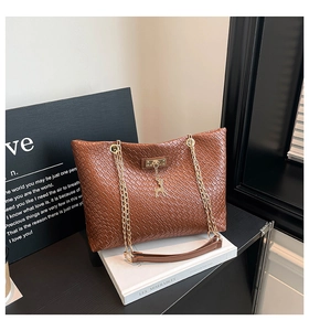 Close-up of brown woven texture leather tote bag with gold chain and deer charm