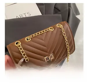 Detailed view of brown quilted crossbody bag with gold chain strap and metal twist lock