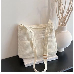 Detail of off-white corduroy tote bag showing front pockets and adjustable strap