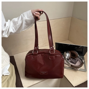Detail of burgundy oil wax leather tote bag with silver rings in a lifestyle office setting