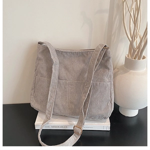Detail of dark grey corduroy tote bag with front pocket on a minimalist background