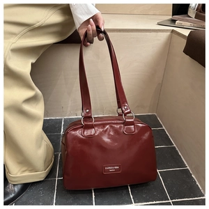 Detail of burgundy leather tote bag with silver metal rings and logo on street floor