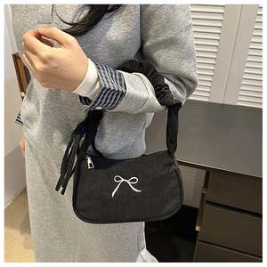 Detail of black corduroy handbag with white bow embroidery and pleated handle design