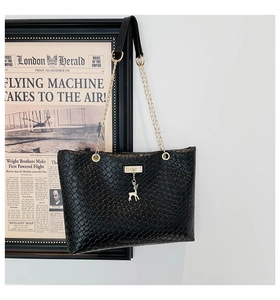 Close-up of black woven bucket bag with gold chain and delicate deer charm detail