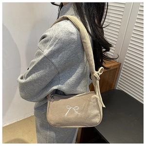 Detail of beige corduroy shoulder bag featuring white embroidered bow decoration