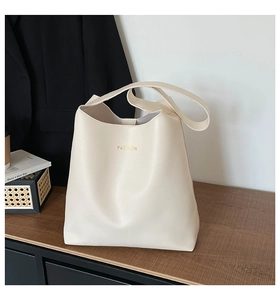 Detail of beige faux leather tote with gold fashion letters on a wooden table surface