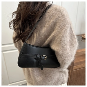 Side view of a minimalist black PU leather underarm bag with gold buckle detail on a model