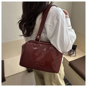 Detailed view of burgundy glossy leather tote bag with brand logo and thick handle