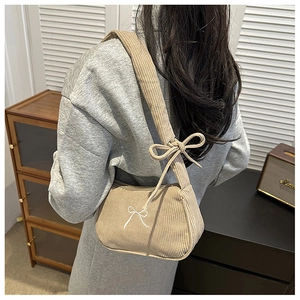 Detailed close-up of corduroy shoulder bag featuring white embroidered bow pattern