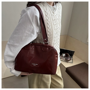 Detail view of large burgundy oil wax leather tote bag worn by a model on shoulder