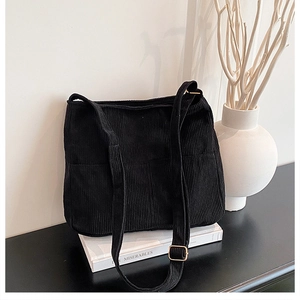 Detail of black corduroy tote bag showing soft ribbed texture and front pockets