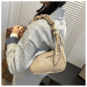 Detail of beige corduroy shoulder bag featuring white bow embroidery and scrunchie strap