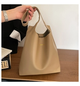 Detail of khaki faux leather tote bag showing gold FASHION lettering and snap closure