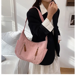 Detail of pink corduroy shoulder bag showing dual zippers and textured fabric surface