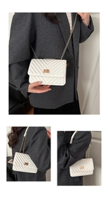 Detail view of white V-quilted faux leather bag with gold twist lock and chain strap