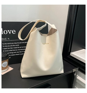 Detail of cream tote bag featuring golden Fashion logo on smooth vegan leather