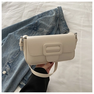 Detail of cream flap crossbody bag with tonal buckle on blue denim and white fabric