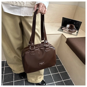 Detail of a brown wax leather tote bag with top handle next to a laptop and magazine