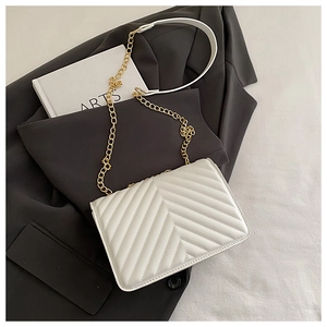 Detail of white V-quilted faux leather crossbody bag with elegant gold chain strap